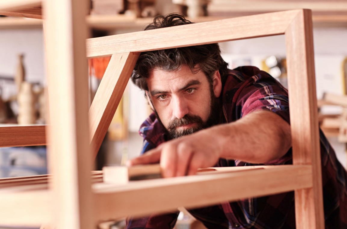 man measuring wood in a workshop